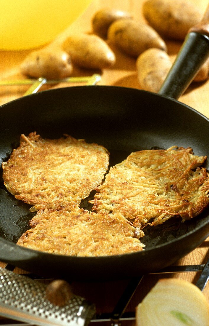 Three potato pancakes (rosti) in a frying pan