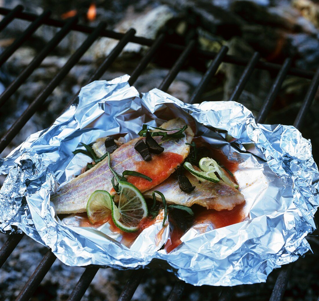Fish fillet (red gurnard) in foil on barbecue