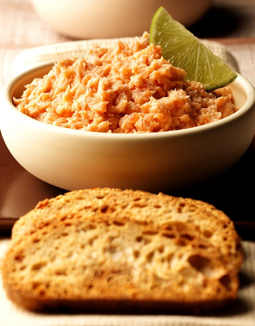 Salmon mousse in bowl, slices of bread in front
