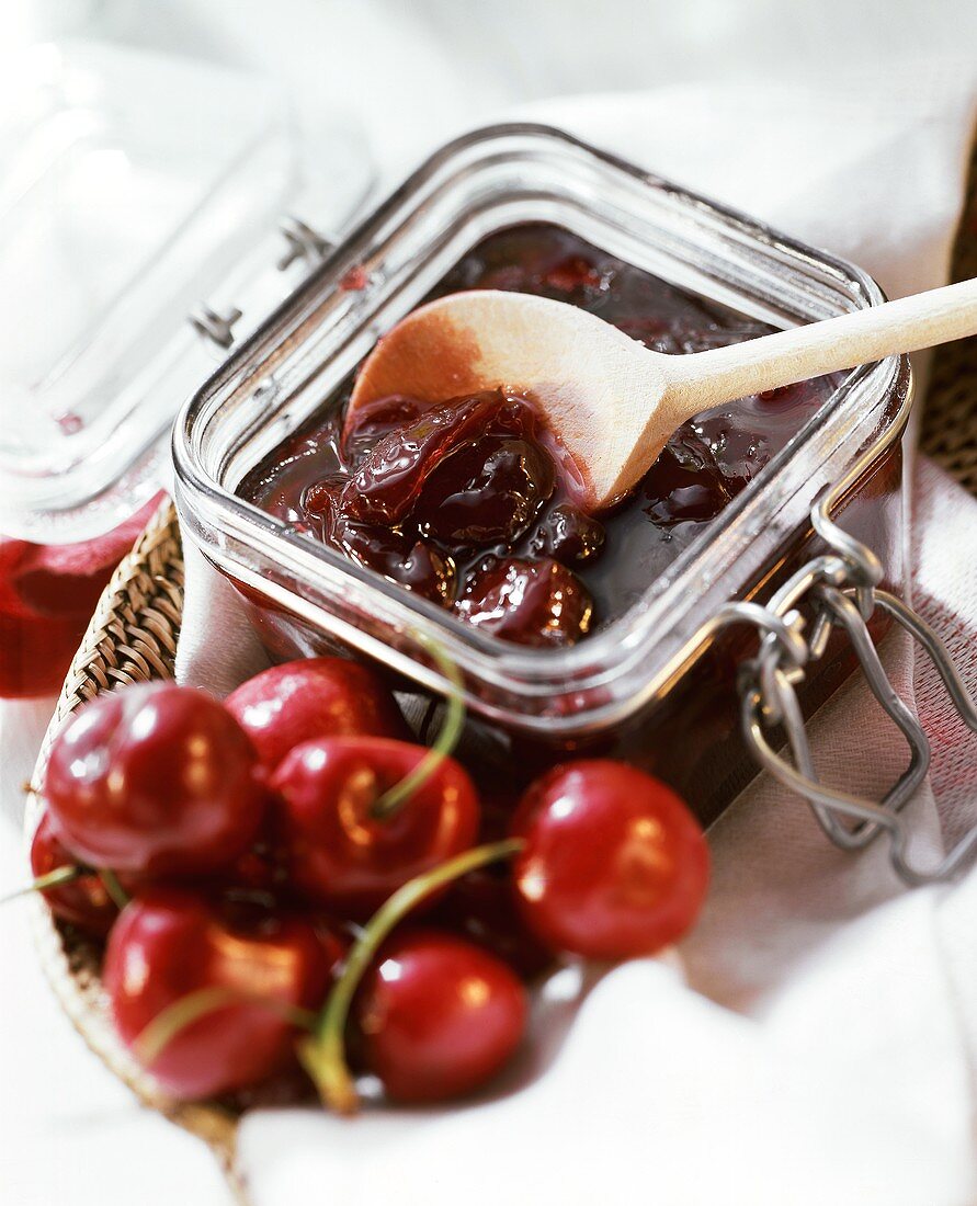 Cherry jam in preserving jar and fresh cherries