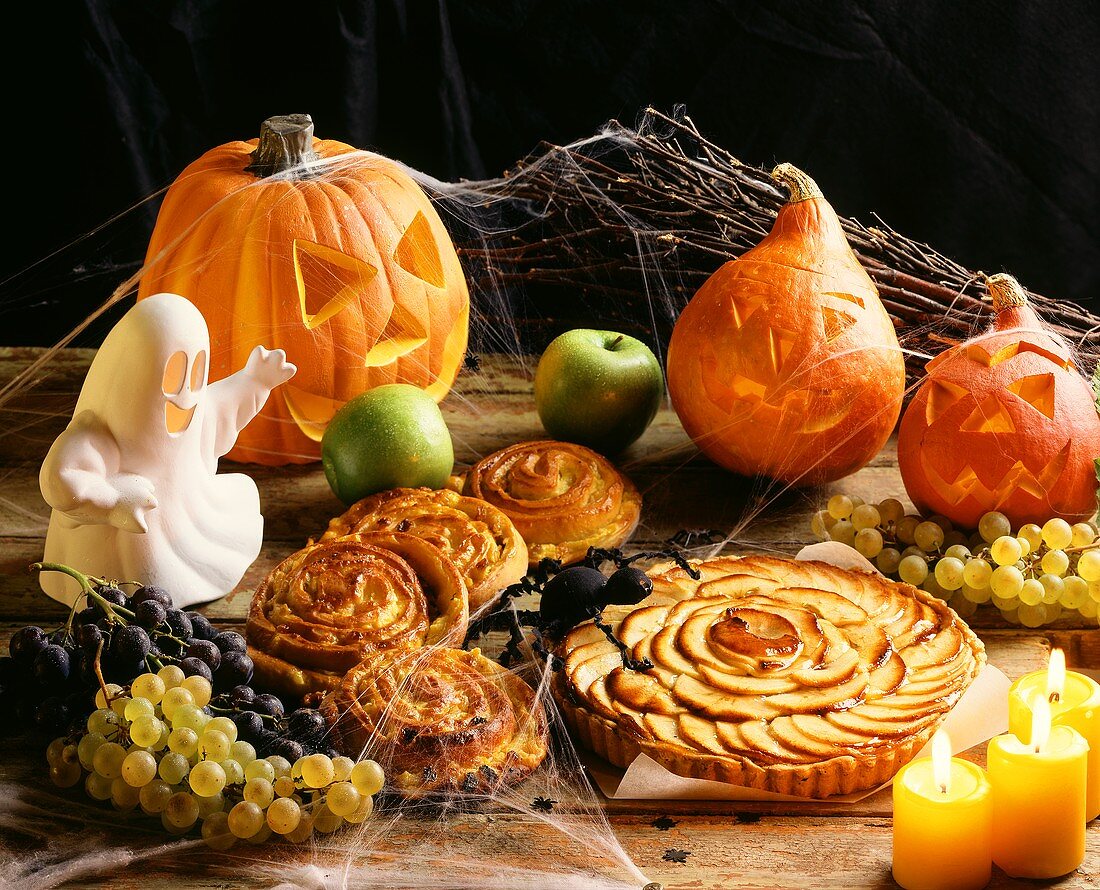 Halloween-Stillleben mit Rosinenschnecken und Apfeltarte