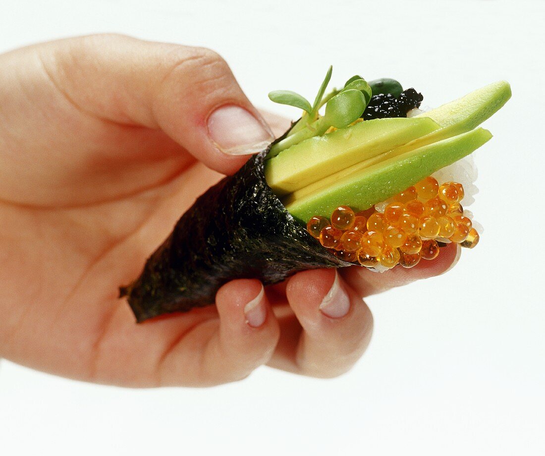 Hand hält Temaki-Sushi mit Lachskaviar und Avocado