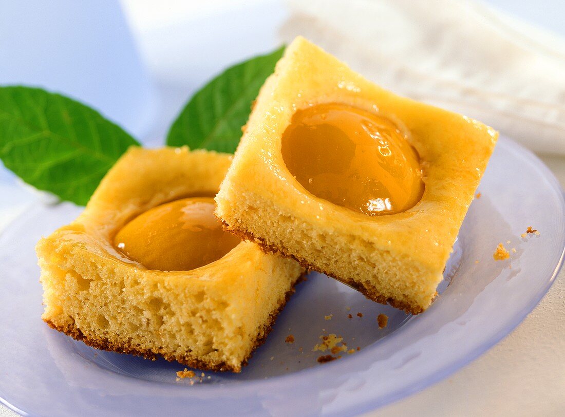 Two pieces of tray-baked peach cake with marzipan