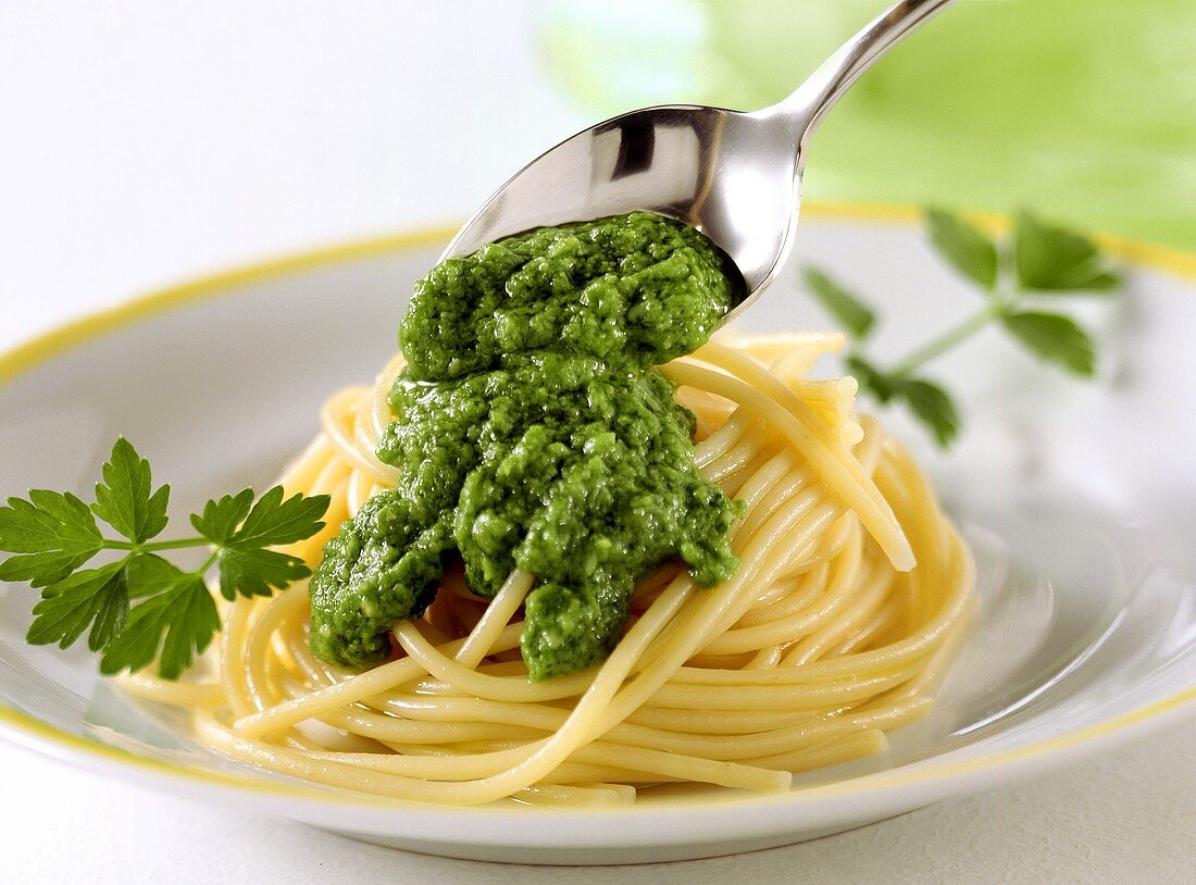 Spooning parsley and almond pesto on to pasta