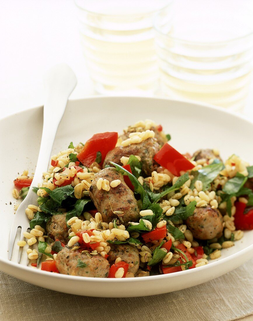 Pan-cooked wheat and vegetable dish with pieces of sausage