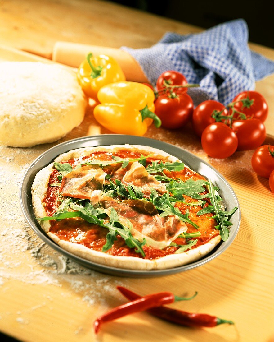 Pizza with tomato sauce, rocket and ham before baking