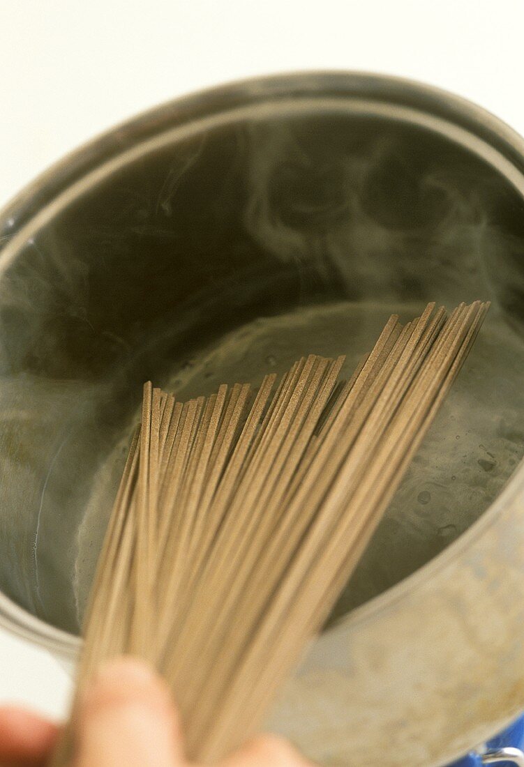 Placing soba noodles in boiling water