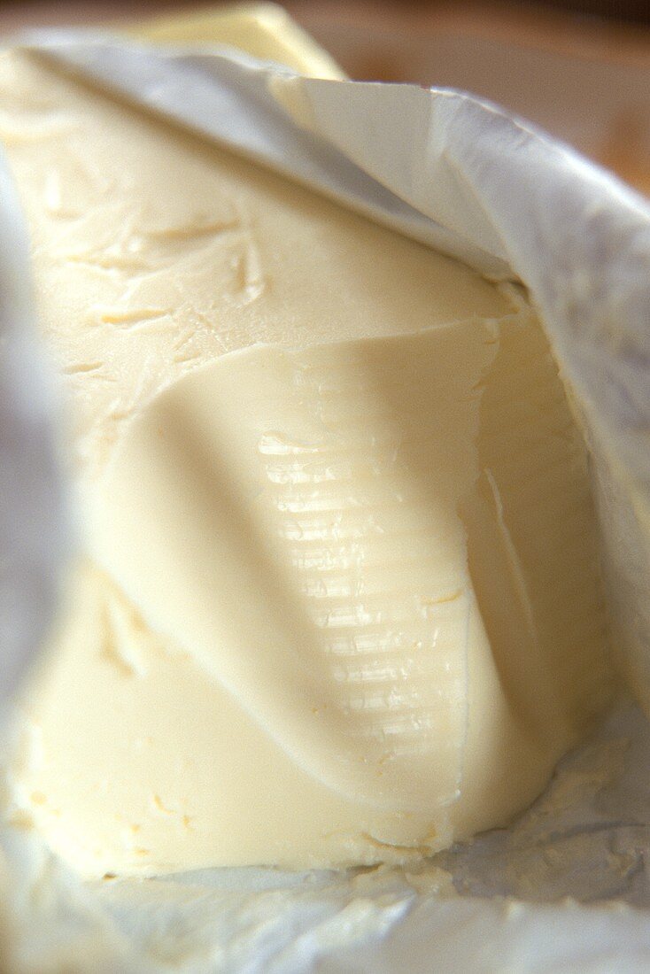 Stück Butter in geöffneter Verpackung