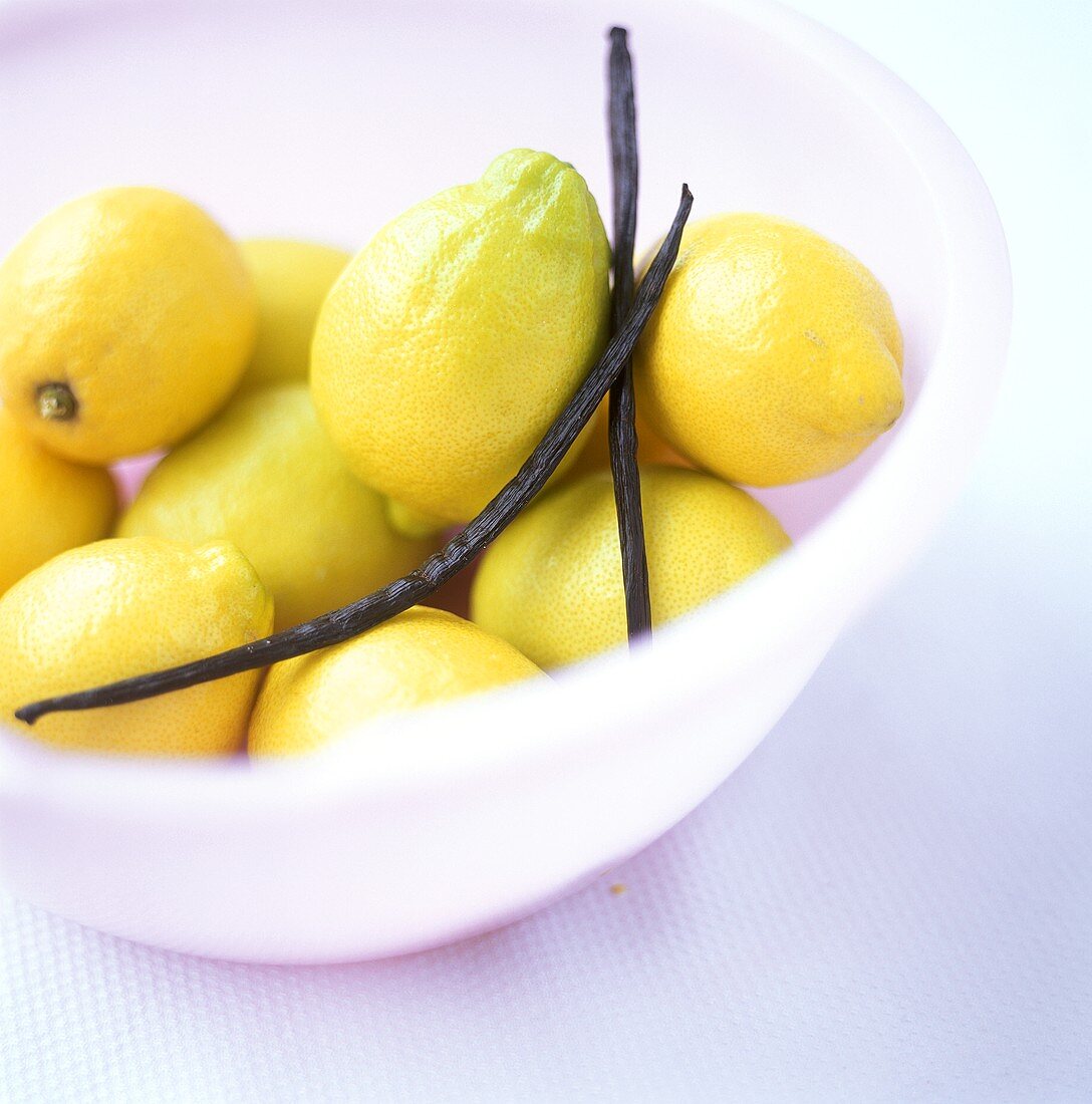 Lemons with vanilla pods in a white dish