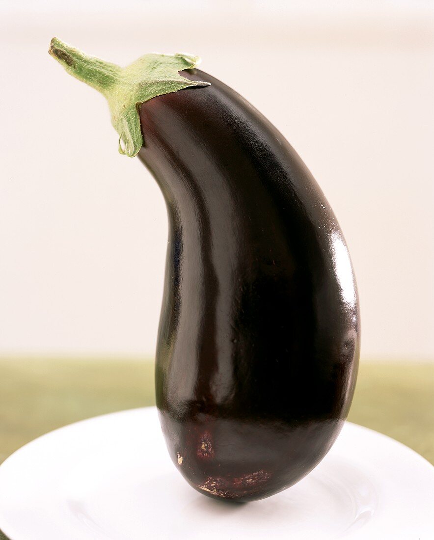 Whole aubergine standing on plate