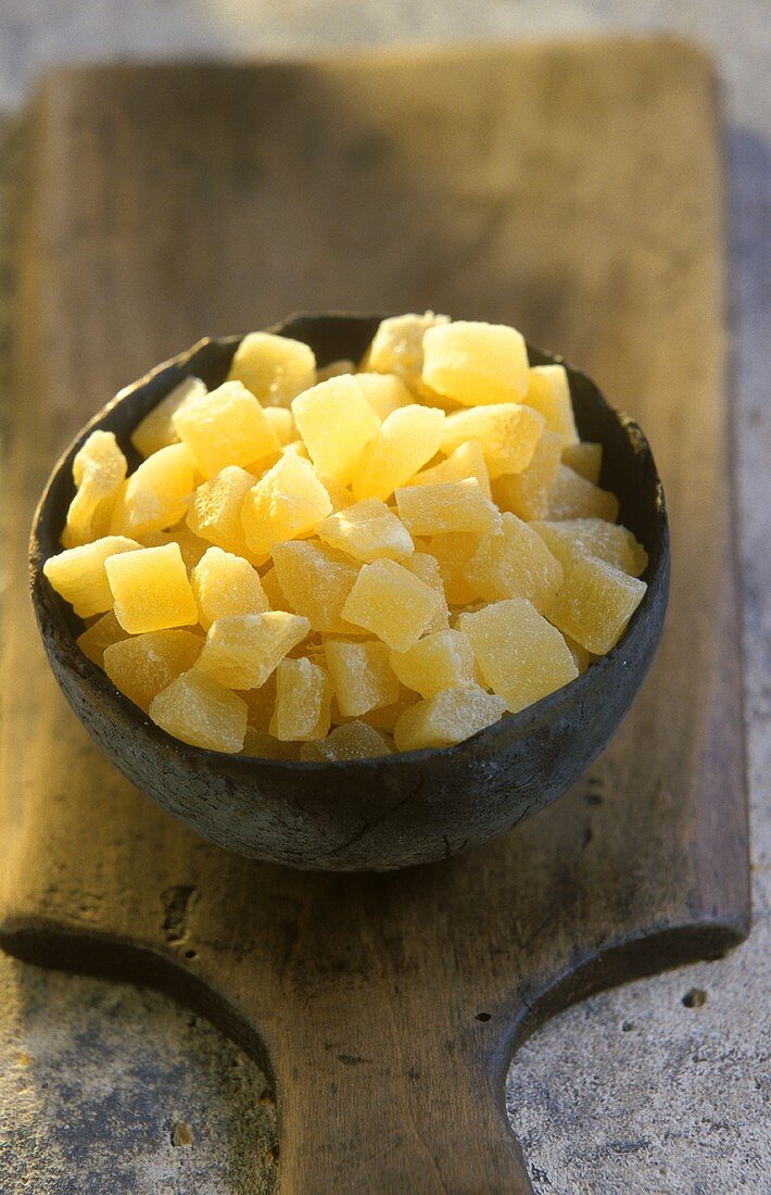Terracotta bowl of candied pineapple on a wooden board