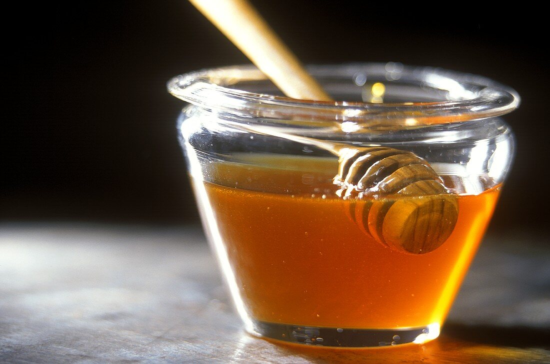 Honey spoon in jar of chestnut honey