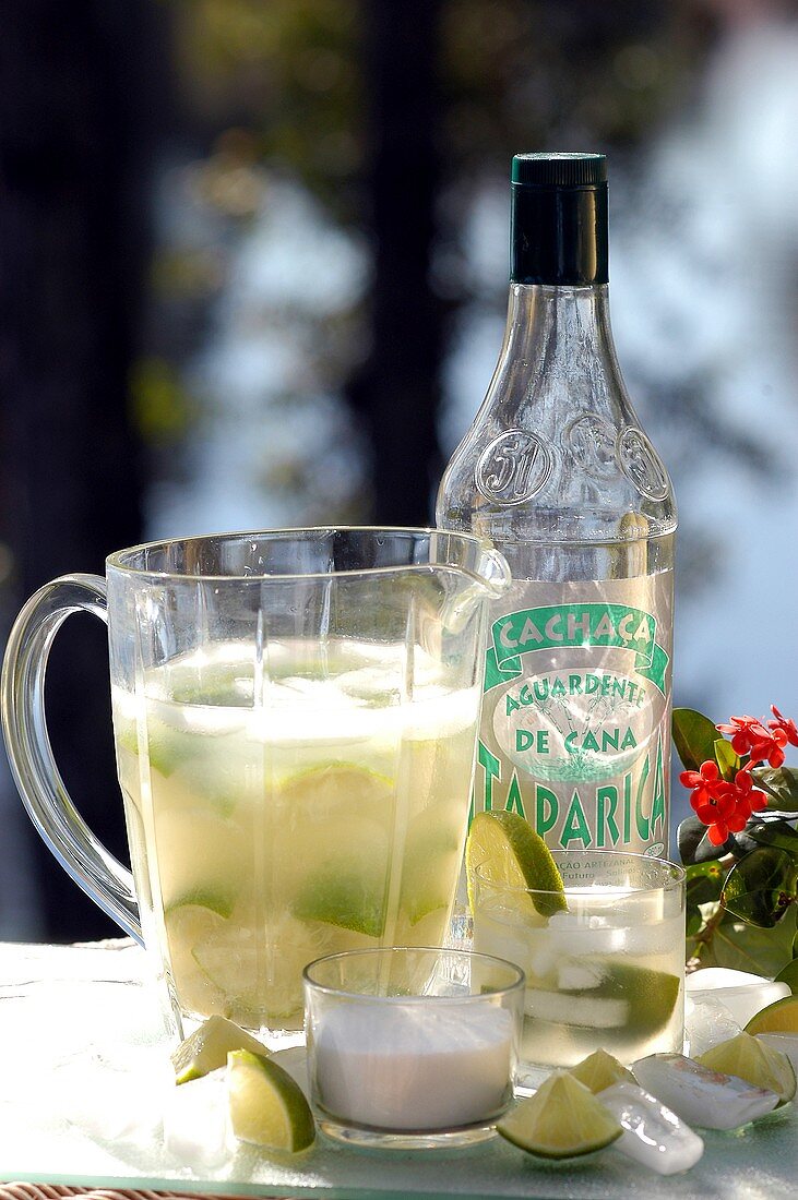 Caipirinha in glass pitcher and bottle of Cachaca Taparica