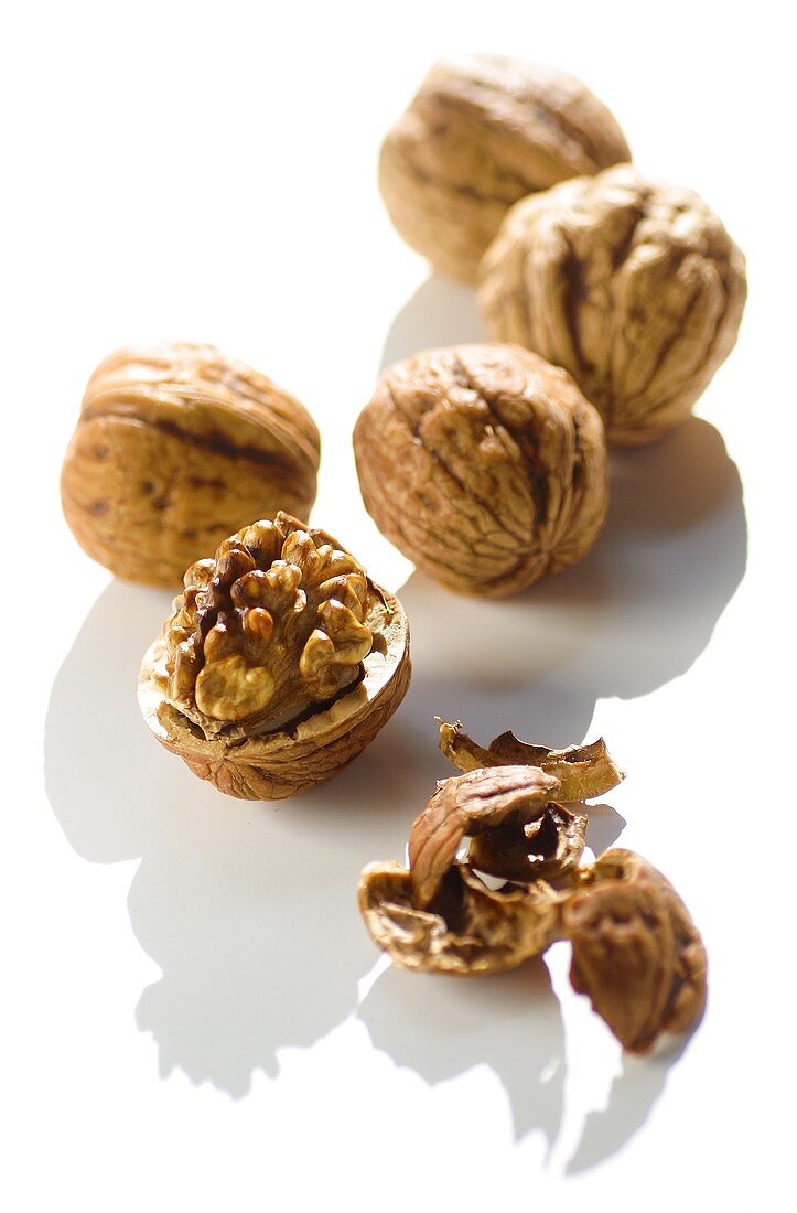 Five walnuts, opened and unopened, on white background