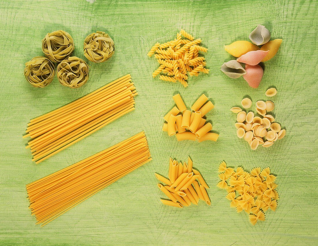 Various types of pasta on green background