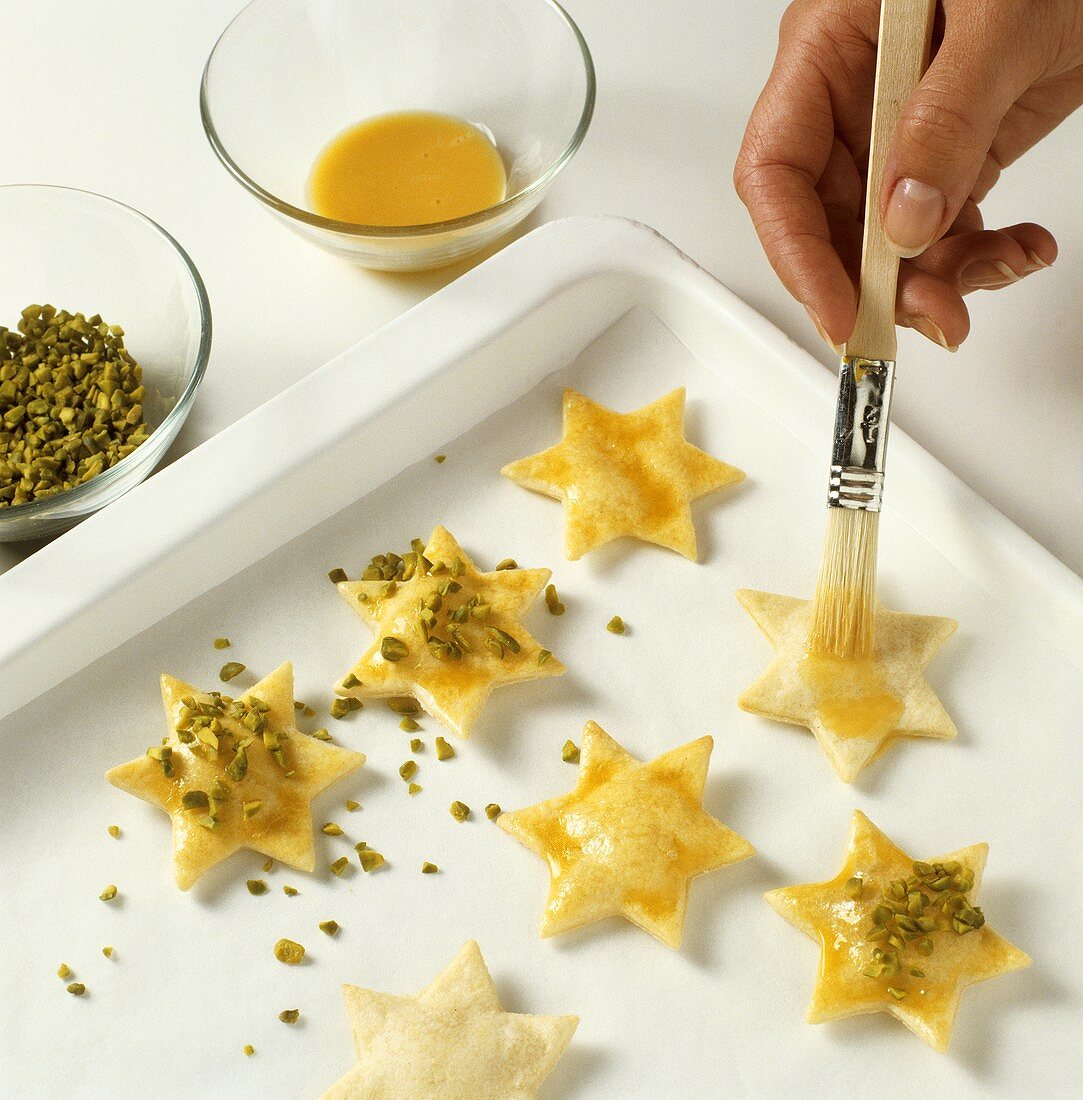 Decorating biscuits with egg yolk glaze and pistachios