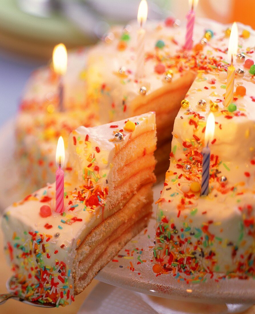 Birthday cake with candles and coloured sprinkles
