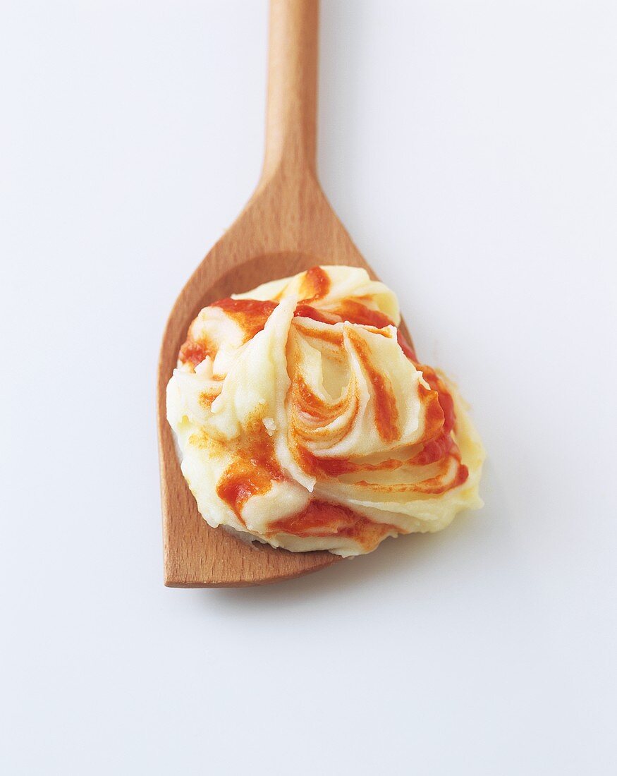 A spoonful of mashed potato with tomato puree