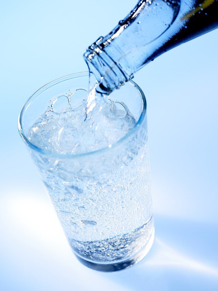 Pouring mineral water out of bottle into glass