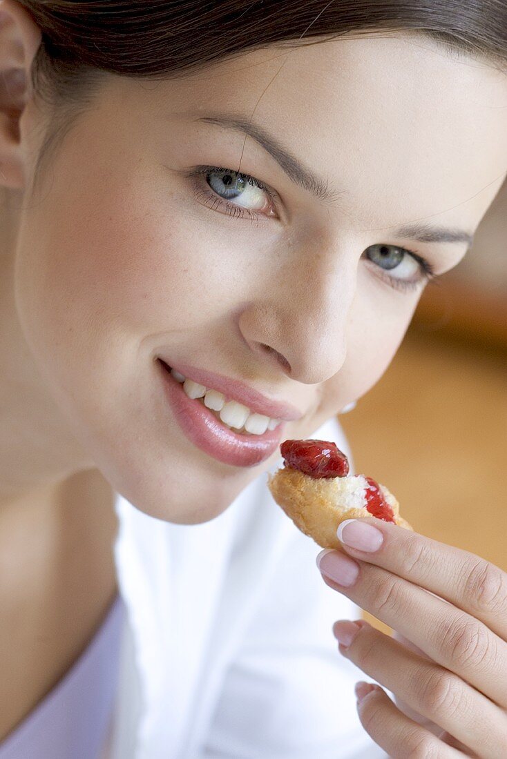 Young woman eating croissant with jam