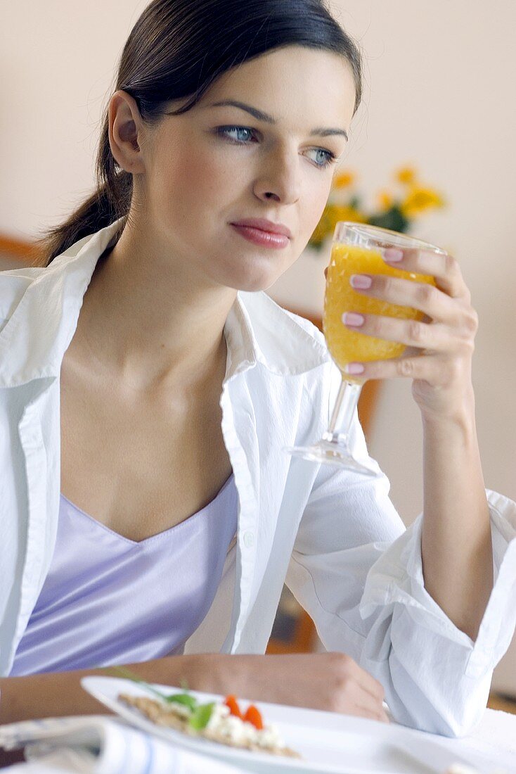 Young woman sitting at table with a glass of orange juice