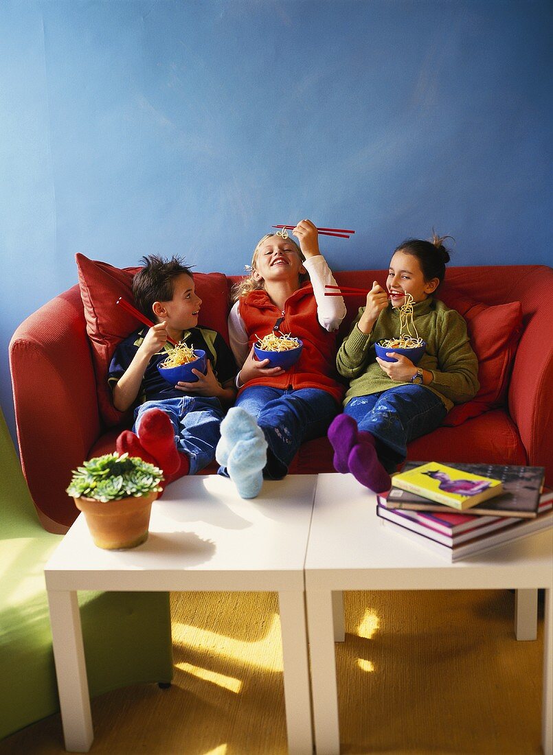 Kinder essen asiatische Nudeln mit Stäbchen