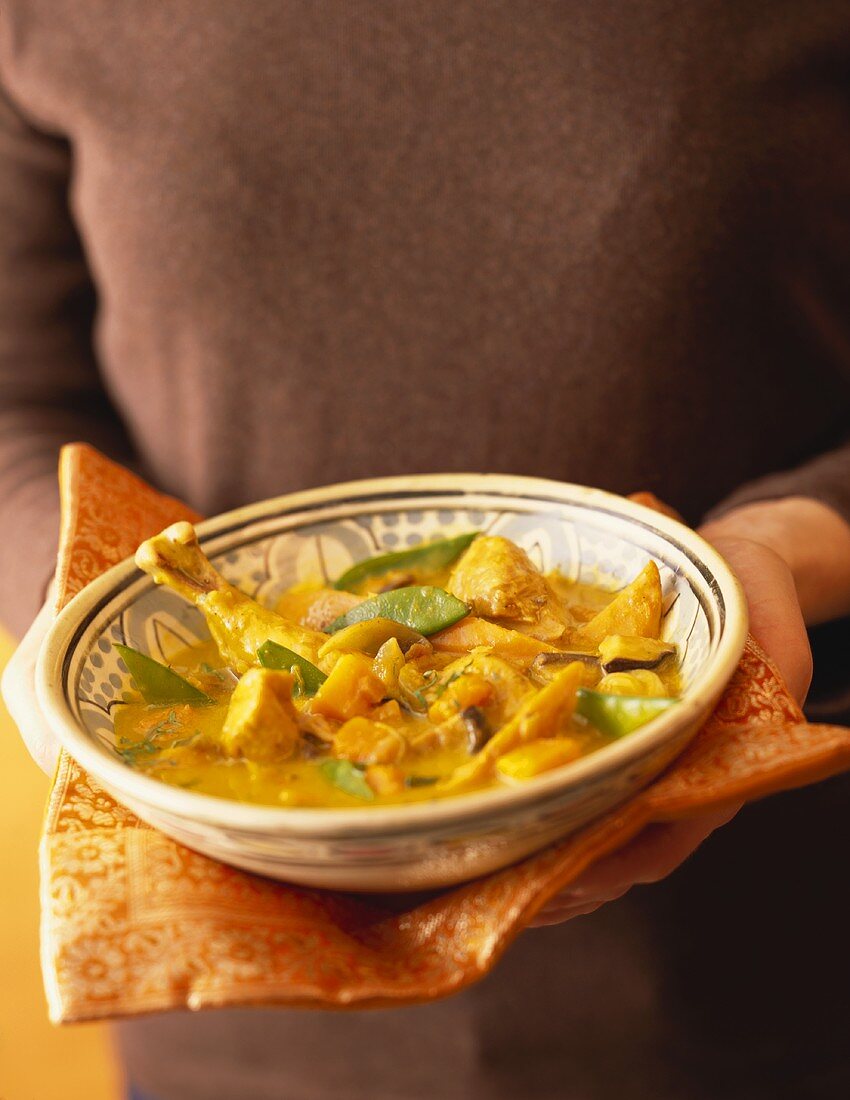 Frau hält Teller mit Kürbis-Hähnchen-Curry