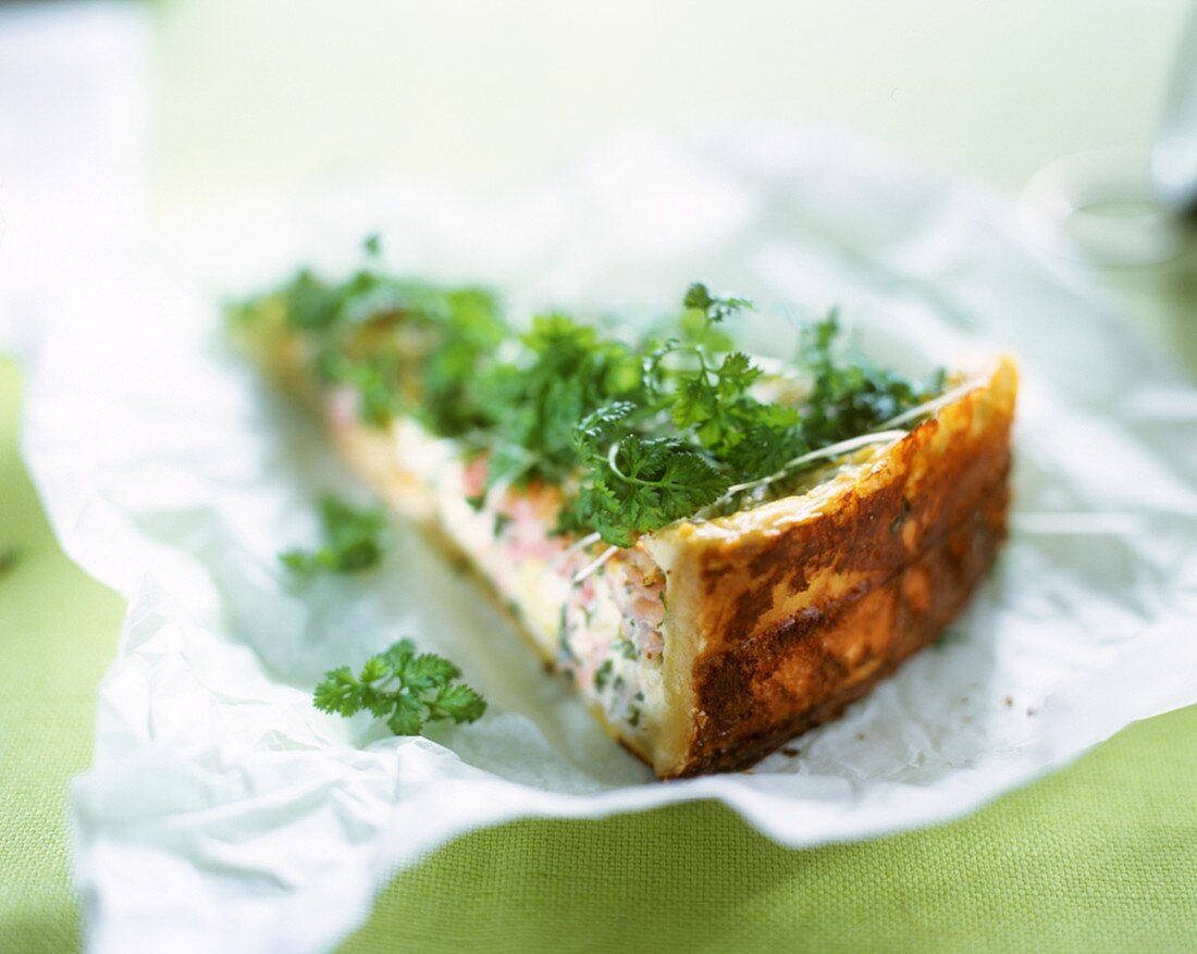 A piece of ham and cheese quiche with herbs