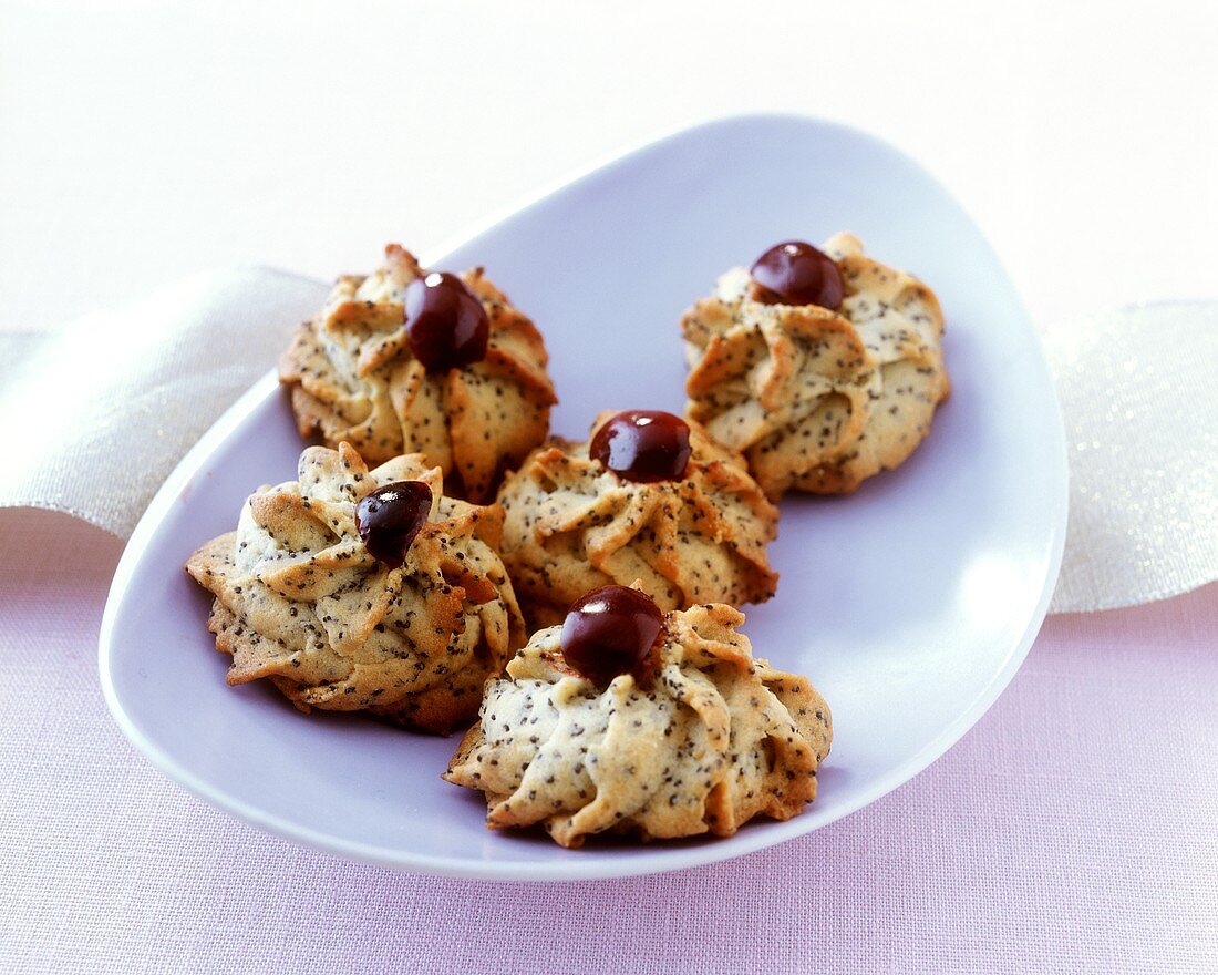 Piped poppy seed biscuits decorated with black cherries