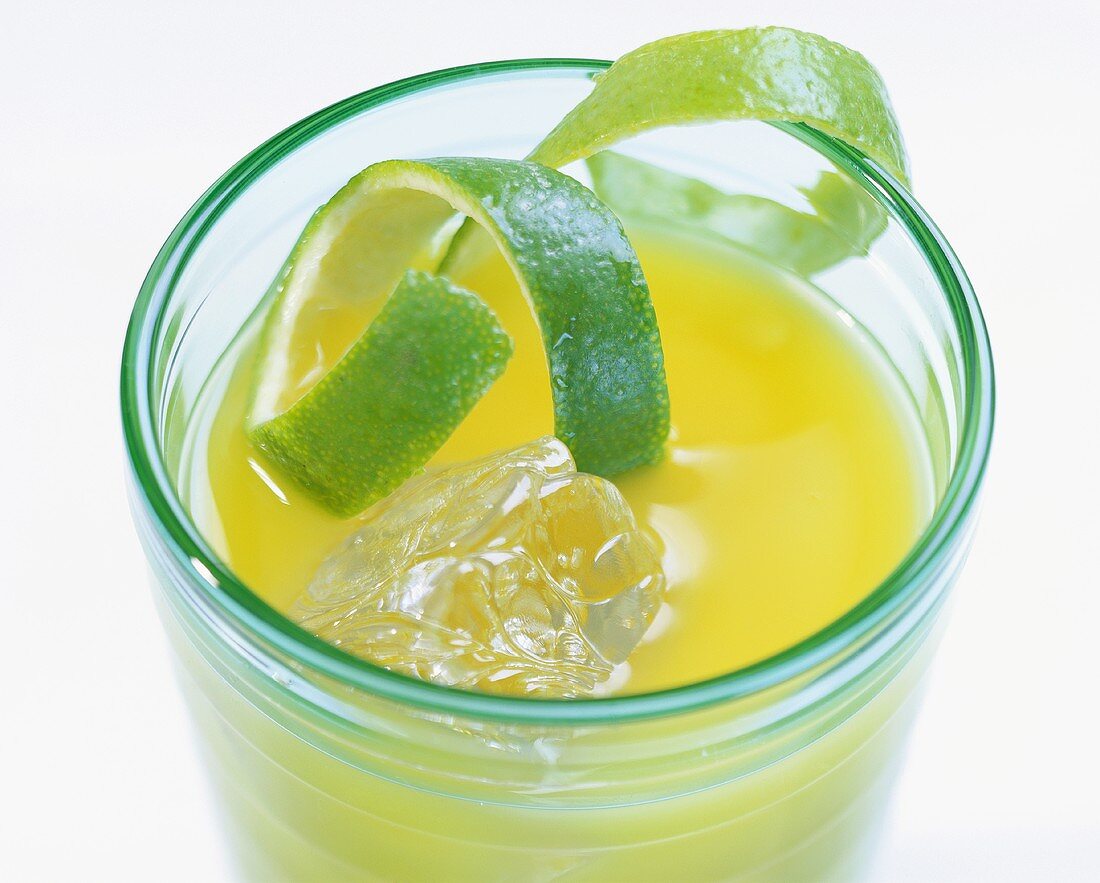 Orange drink with ice cubes and lime peel