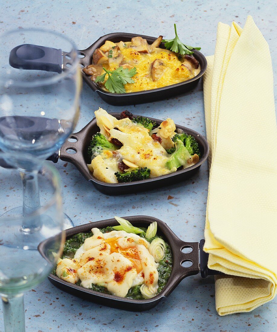Käsepilze, Kohlröschen und Ei auf Spinat in Raclettepfännchen