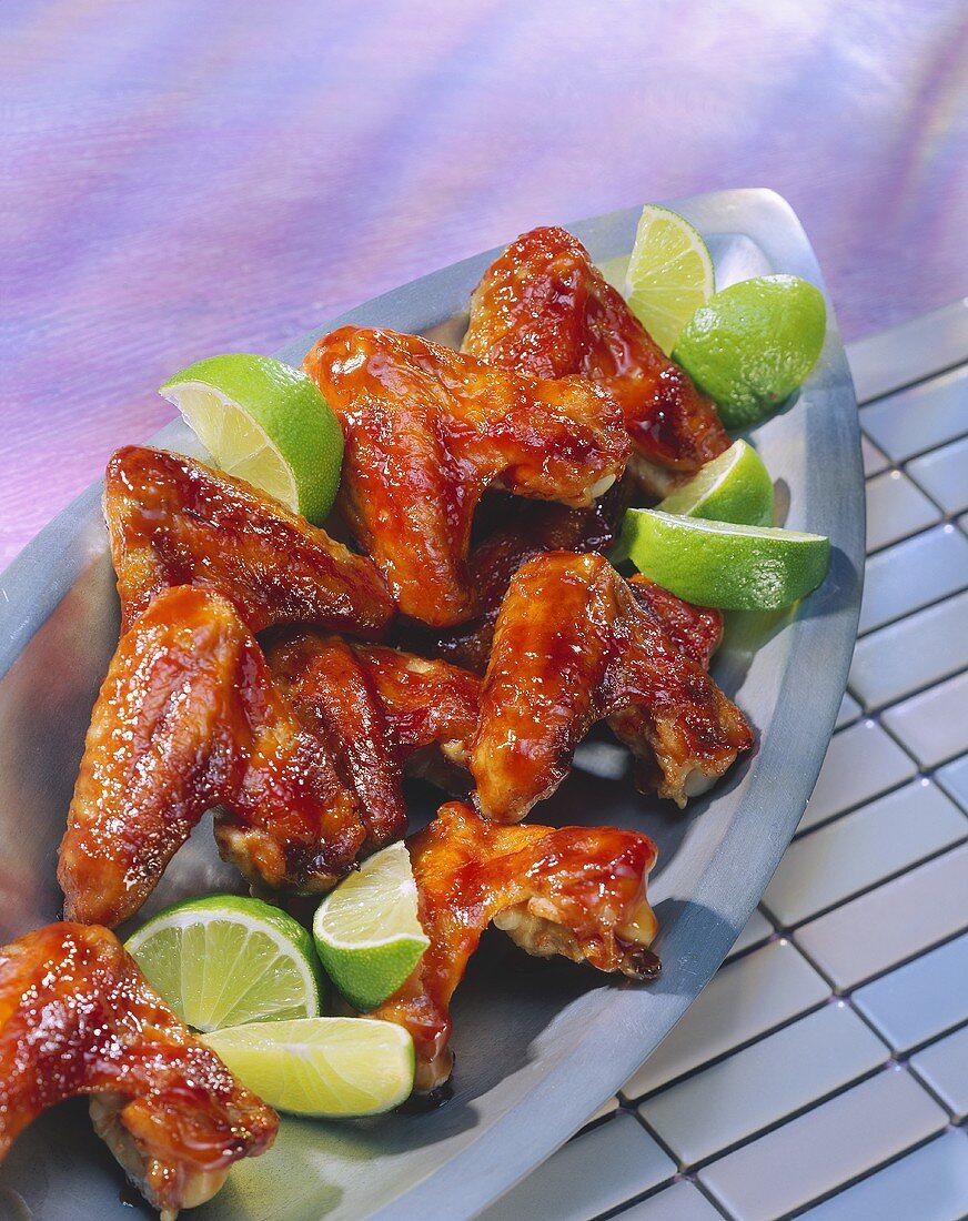 Barbecued chicken wings with lime wedges
