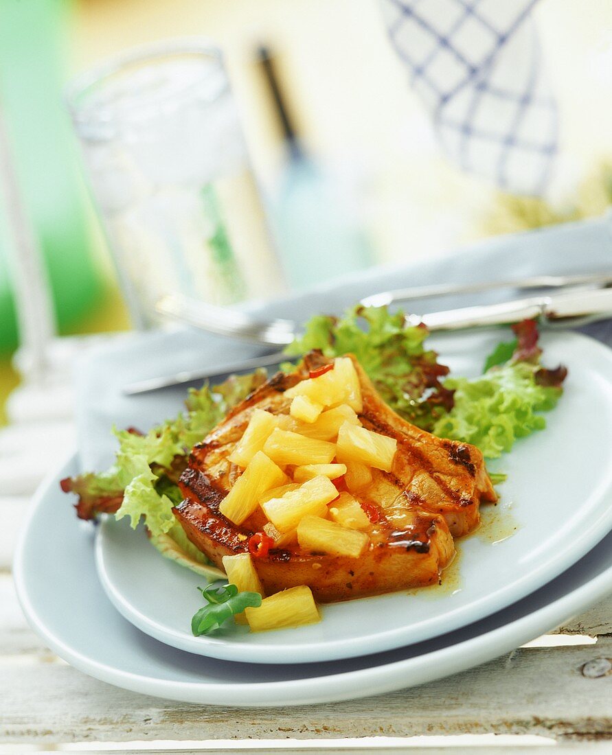 Pork chop with pieces of fresh pineapple and salad leaves