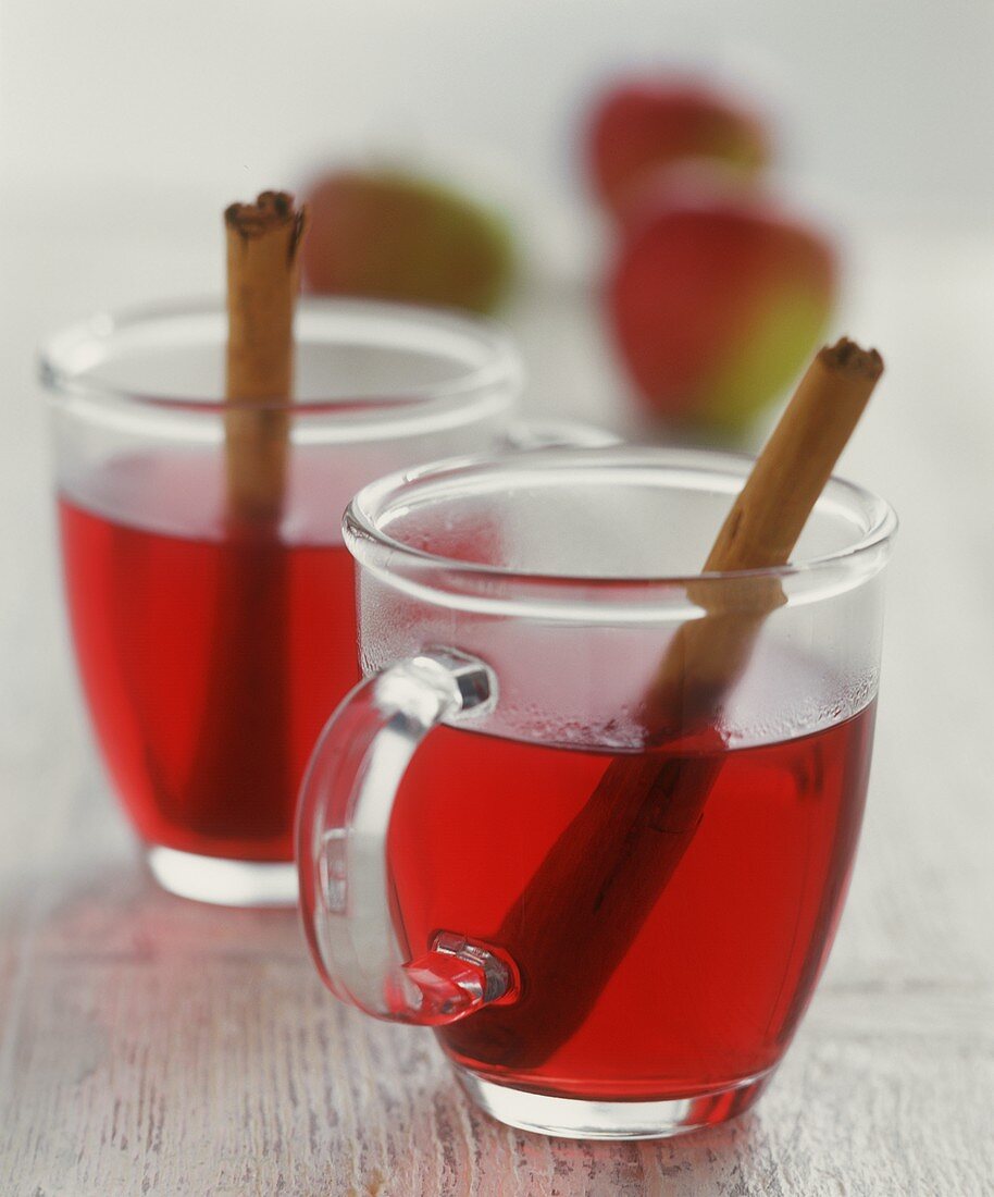 Two glass mugs of mulled wine with cinnamon sticks