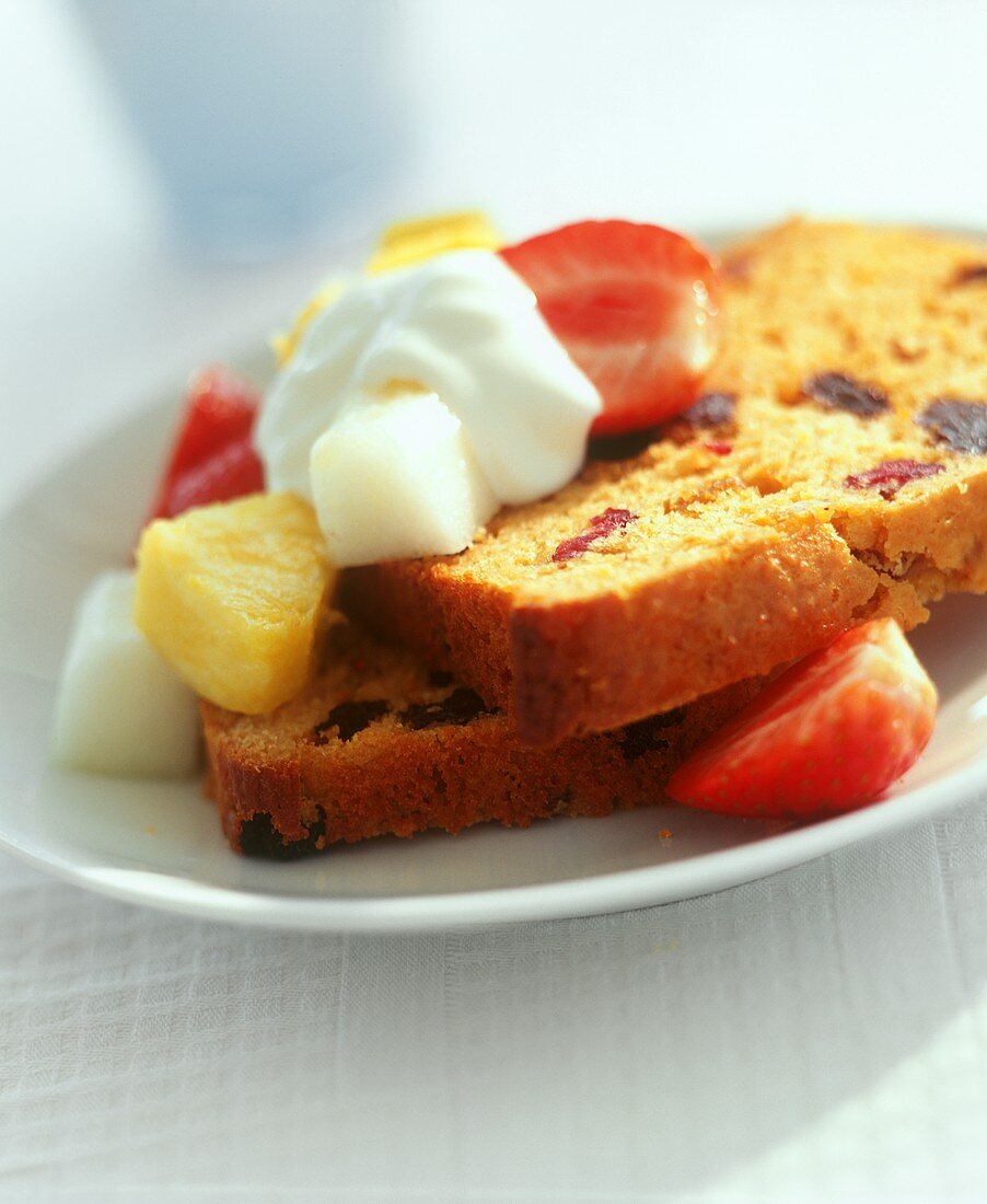 Two slices of Madeira cake with dried fruit, fresh fruit