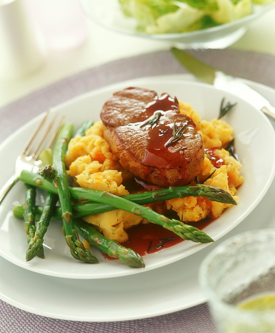 Beef steak on mashed potato and pumpkin with green asparagus