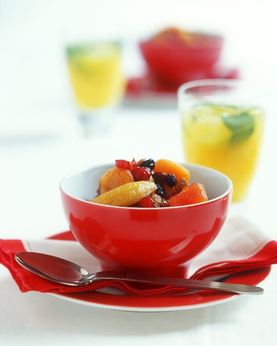 Fruit salad in a red bowl, a spoon beside it