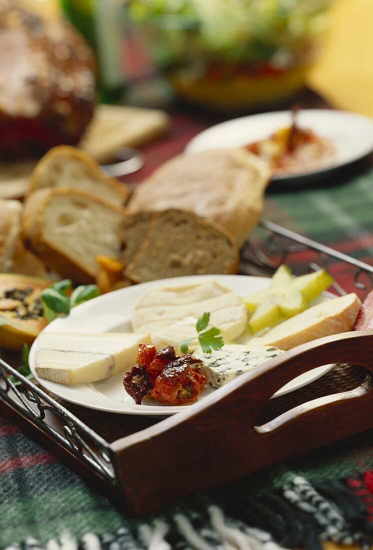 Cheese platter with dried tomatoes, bread behind