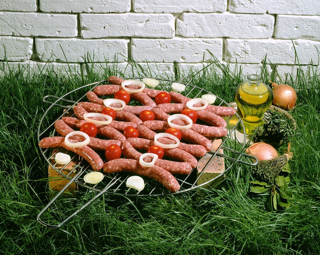 Chipolata sausages on a grill rack in grass