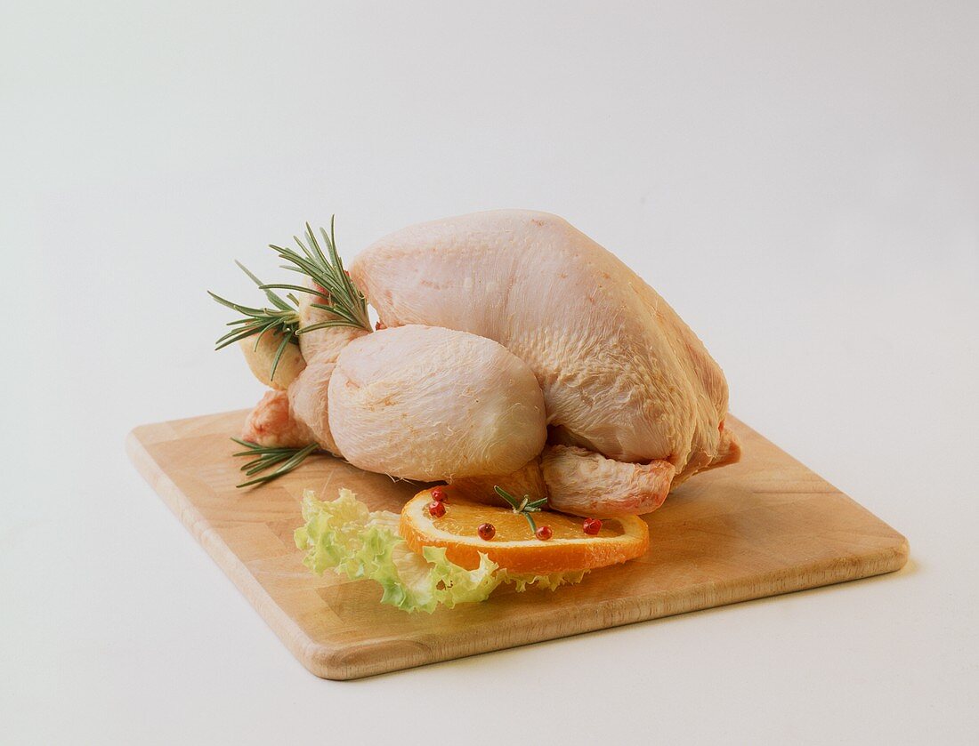 Trussed boiling fowl on wooden board