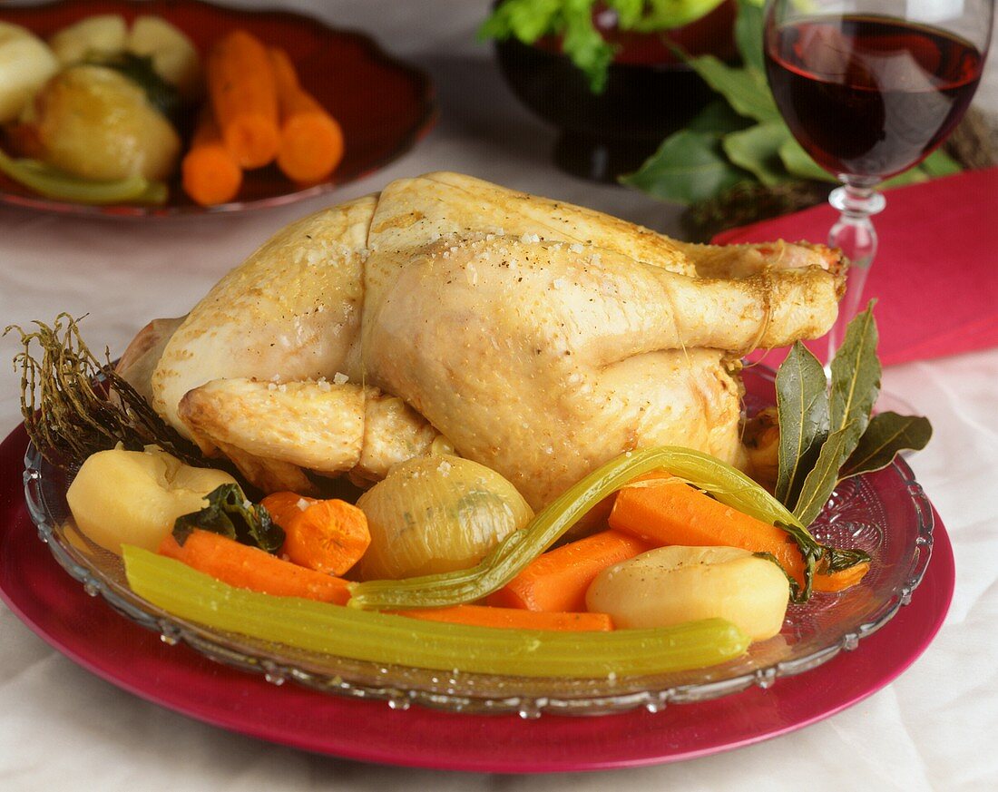 Whole cooked chicken with sea salt on bed of vegetables