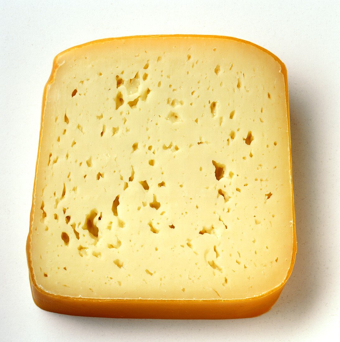 A slice of Tilsit cheese with rind