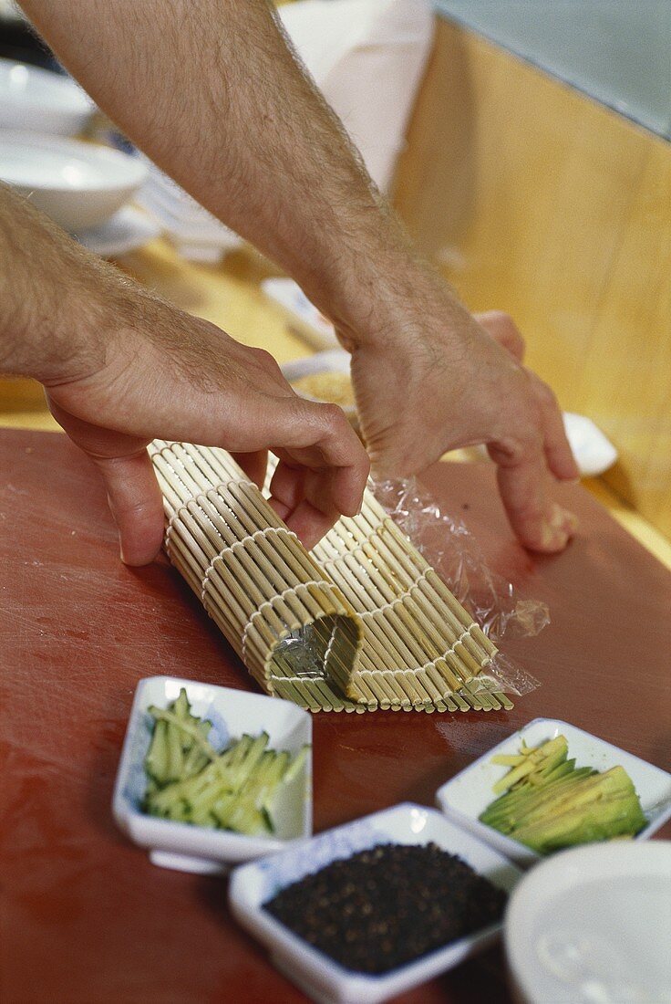 Sushi mit Hilfe einer Bambusmatte rollen