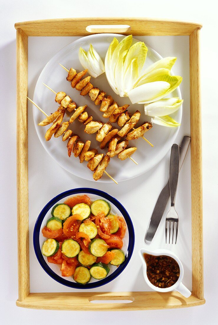 Chicken kebabs with chicory and tomato and courgette salad