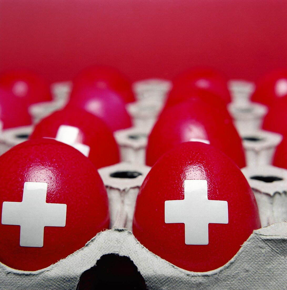 Dyed red eggs with Swiss cross in egg box
