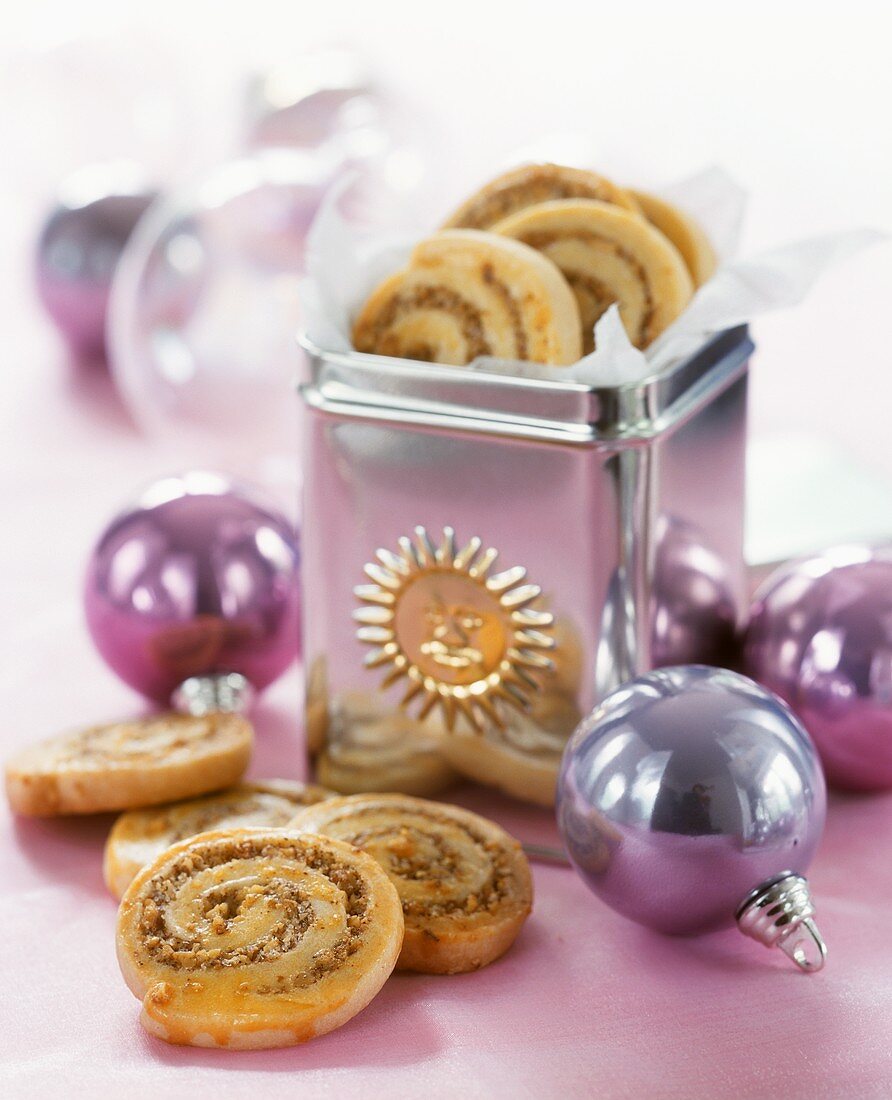 Spiral-shaped nut biscuits in and in front of biscuit tin