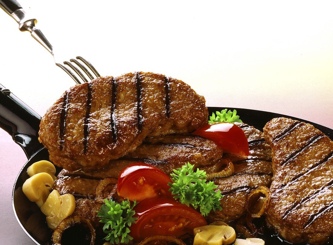 Vienna steaks with mushrooms and vegetables in pan