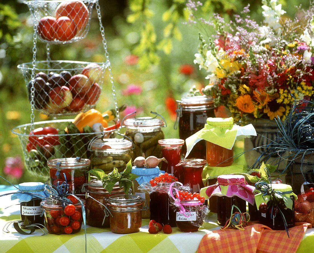 Stillleben mit eingemachtem Gemüse und Obst auf Gartentisch