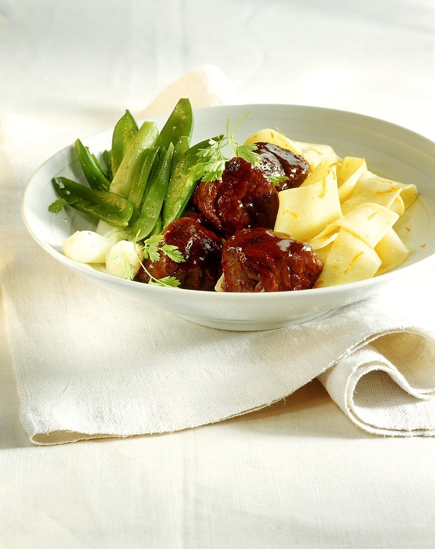Lamb ragout with noodles in orange butter and mangetouts