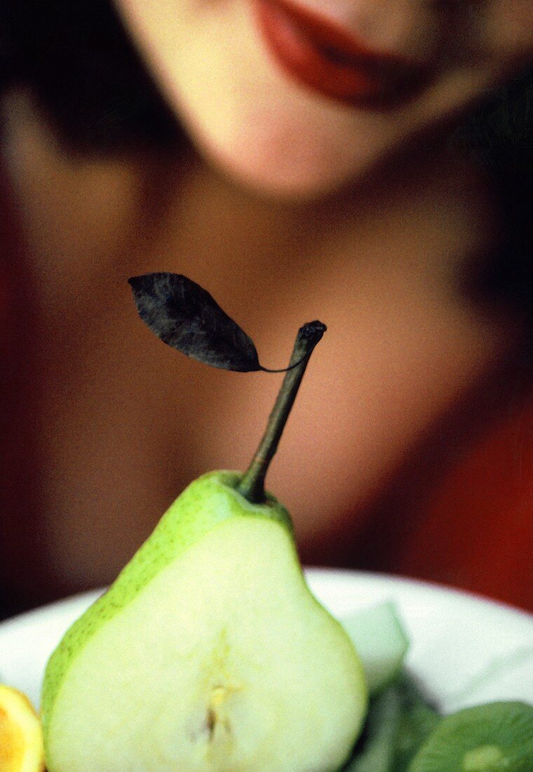 Pear in front of woman with red lips (close-up)